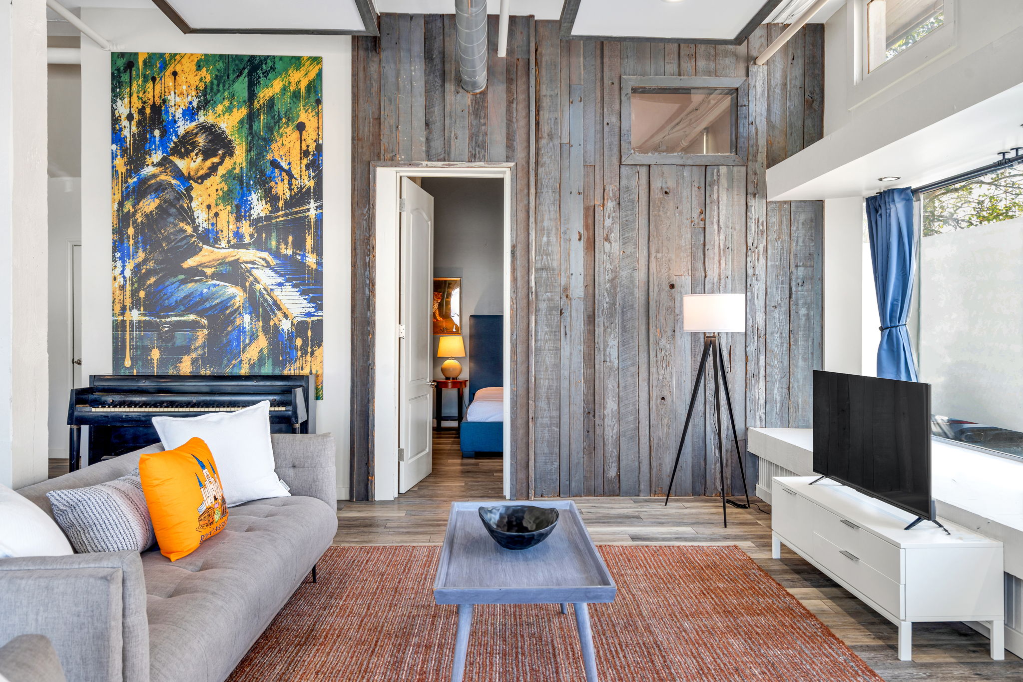 The Harry Connick Jr. mural and the suite&rsquo;s upright piano against the reclaimed-wood wall in The Ivories