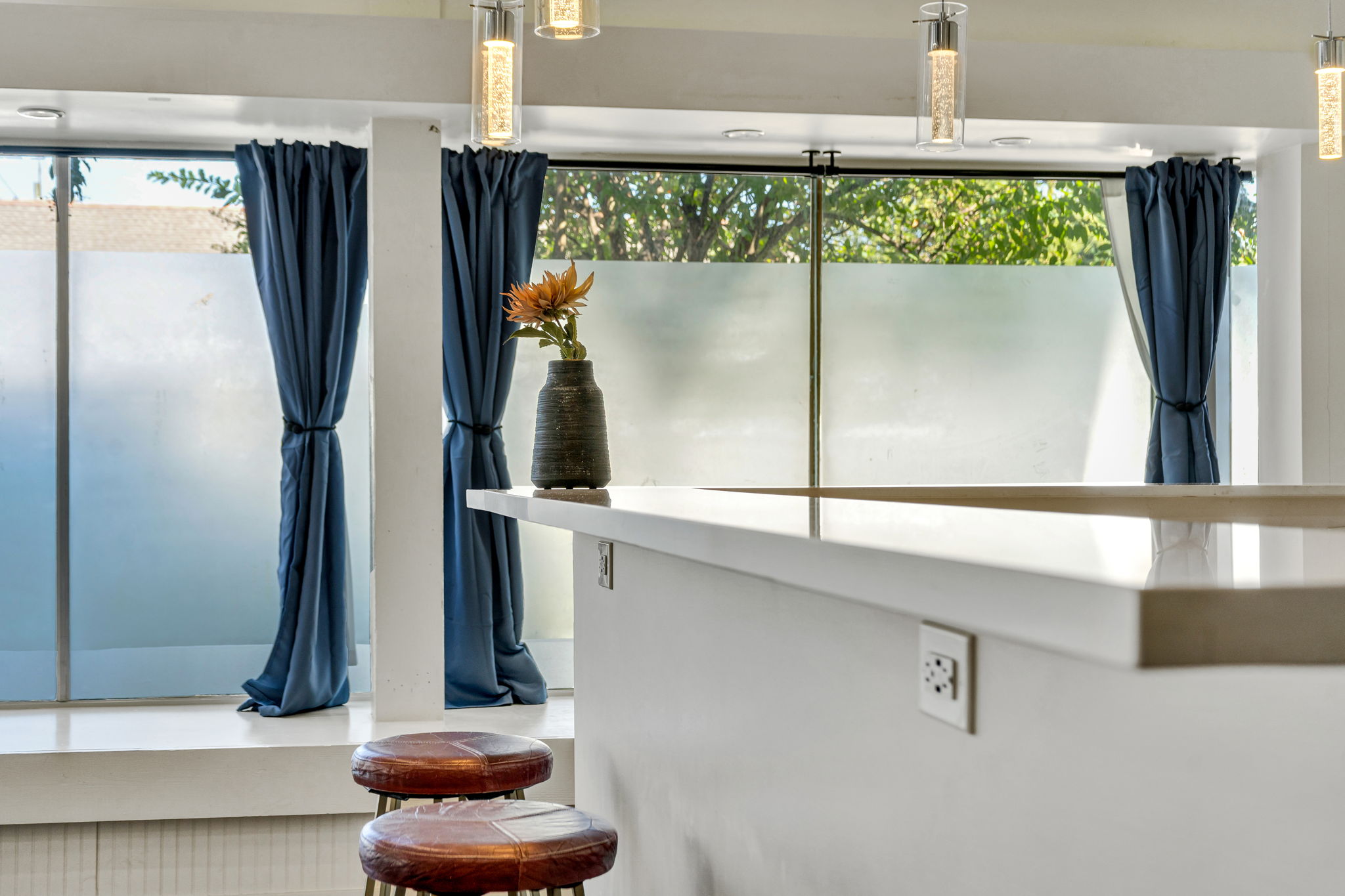 The kitchen bar counter in The Ivories suite, with brown leather stools and pendant lights