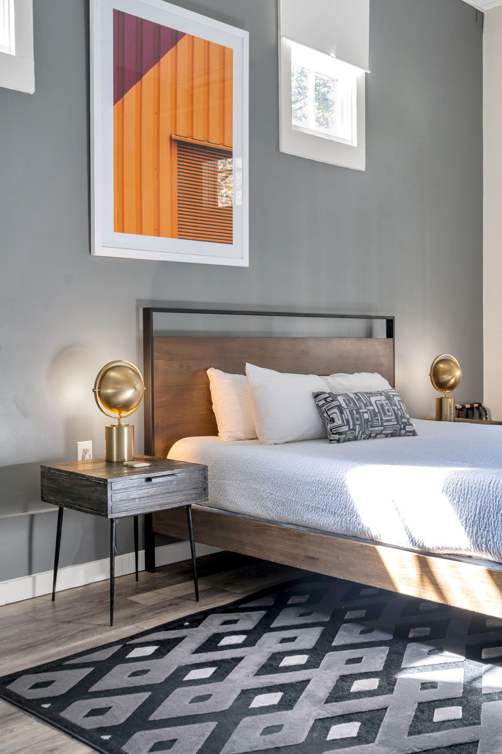 A bedroom in The Ivories suite with brass globe lamps and orange artwork