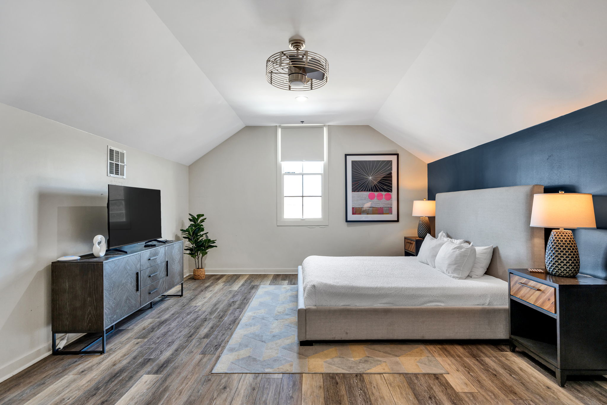 The navy-wall bedroom in The Ivories suite, seen from the opposite side with the TV and dresser