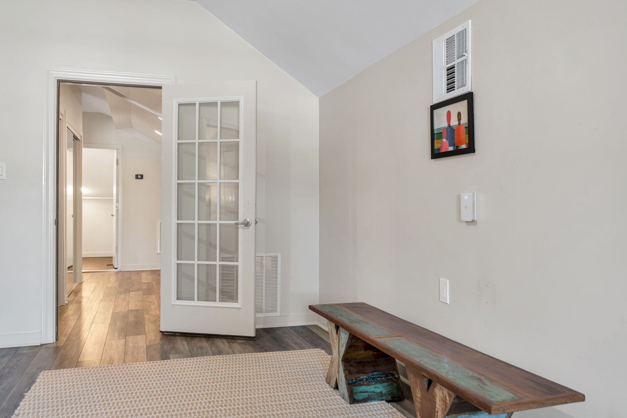 A hallway in The Ivories suite with a French door and a rustic wooden bench
