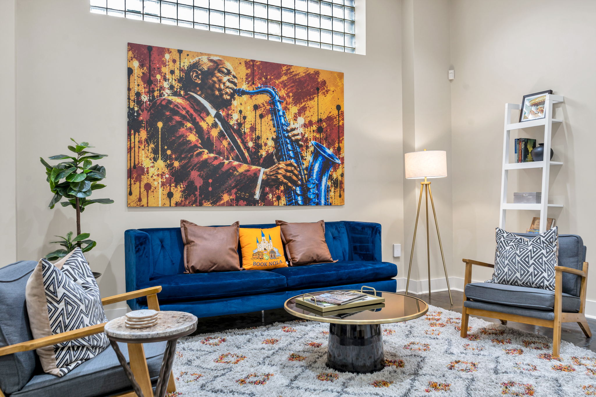 The Sidney Bechet mural straight-on above the blue velvet sofa in The Reed suite, glass-block windows above