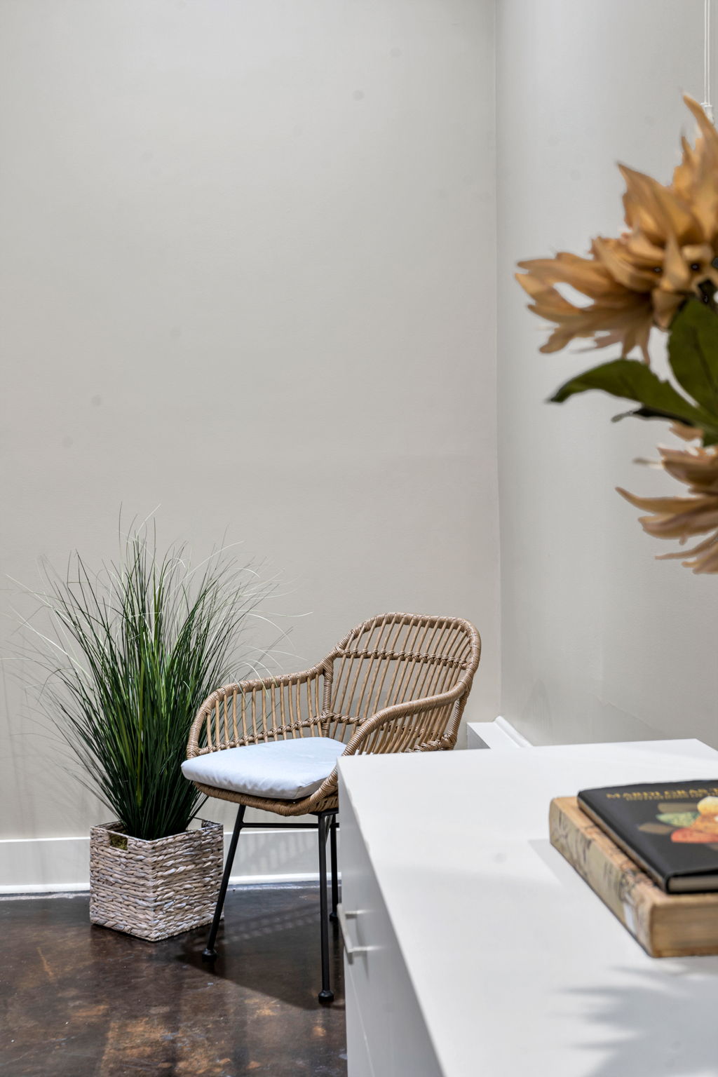 Wicker chair and potted plant beside the white dresser in The Reed suite