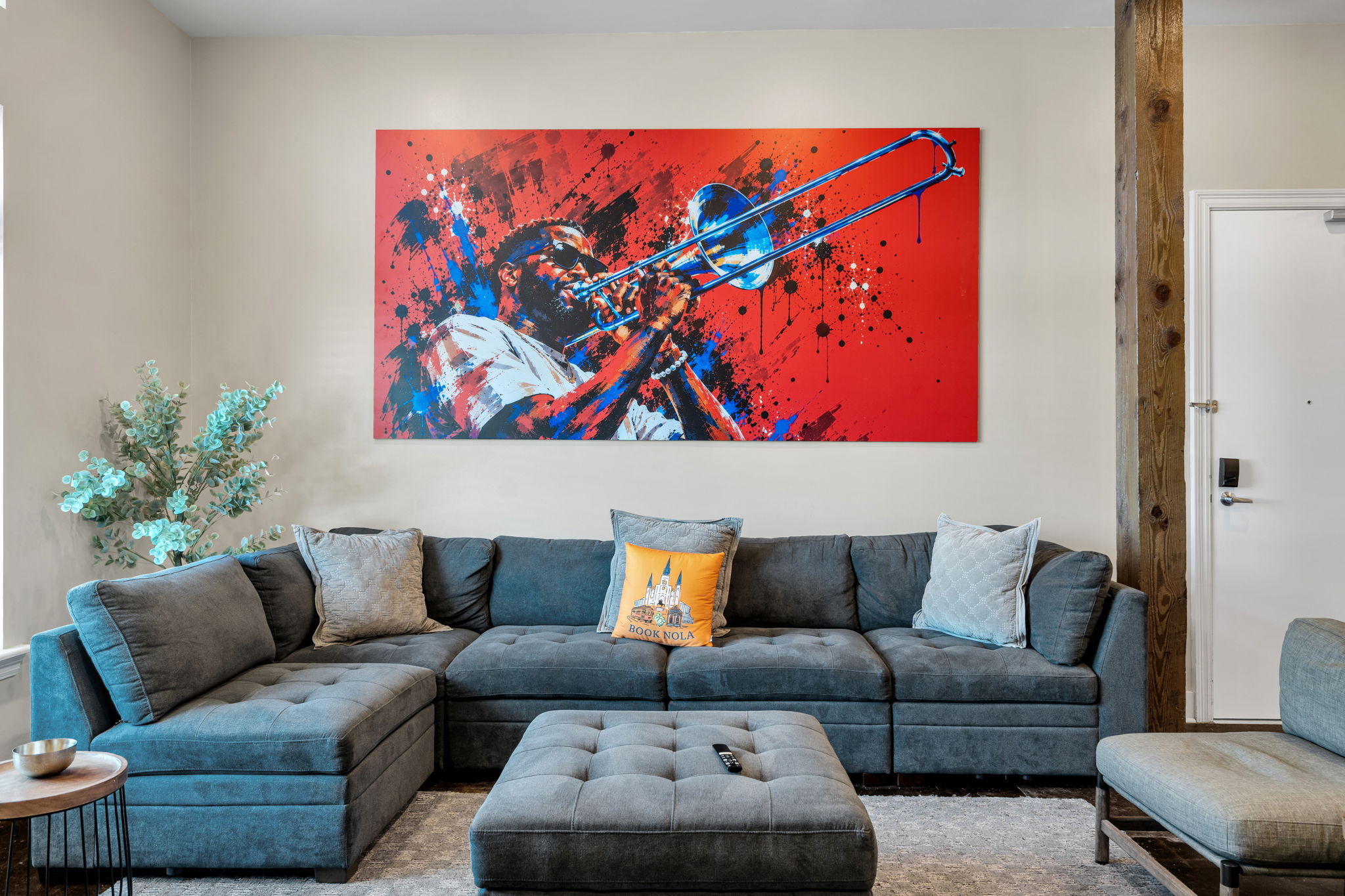 The Trombone Shorty mural straight-on above the gray sectional sofa in The Slide suite