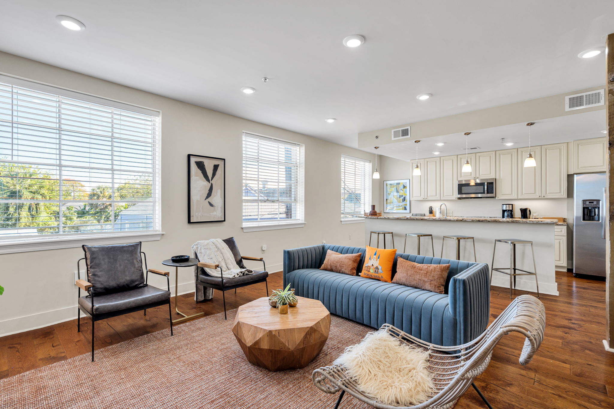 Wide open-plan living room with the blue sofa and the kitchen beyond in The Bell suite