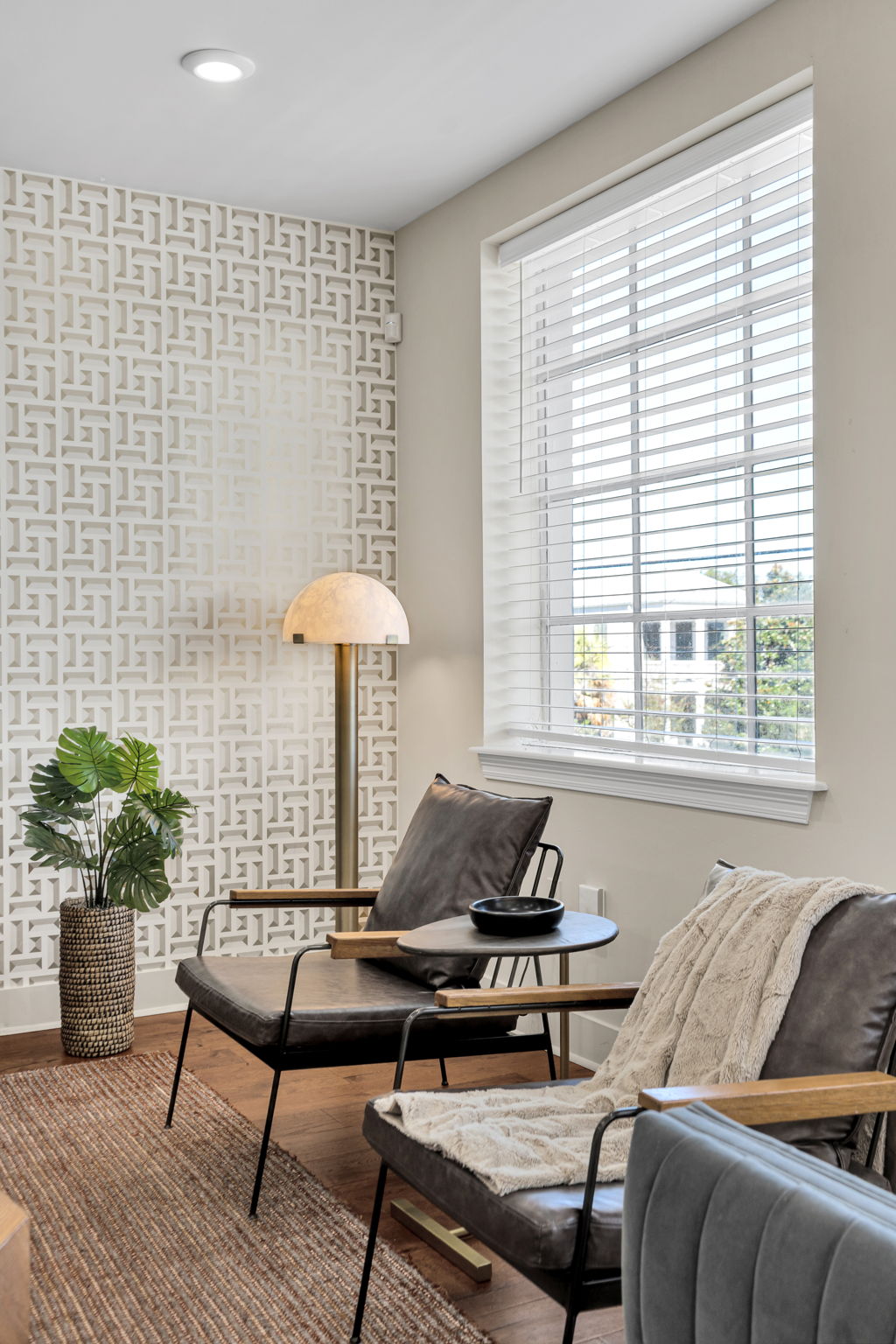 Sitting corner with geometric wallpaper, leather chairs, and a dome floor lamp in The Bell suite