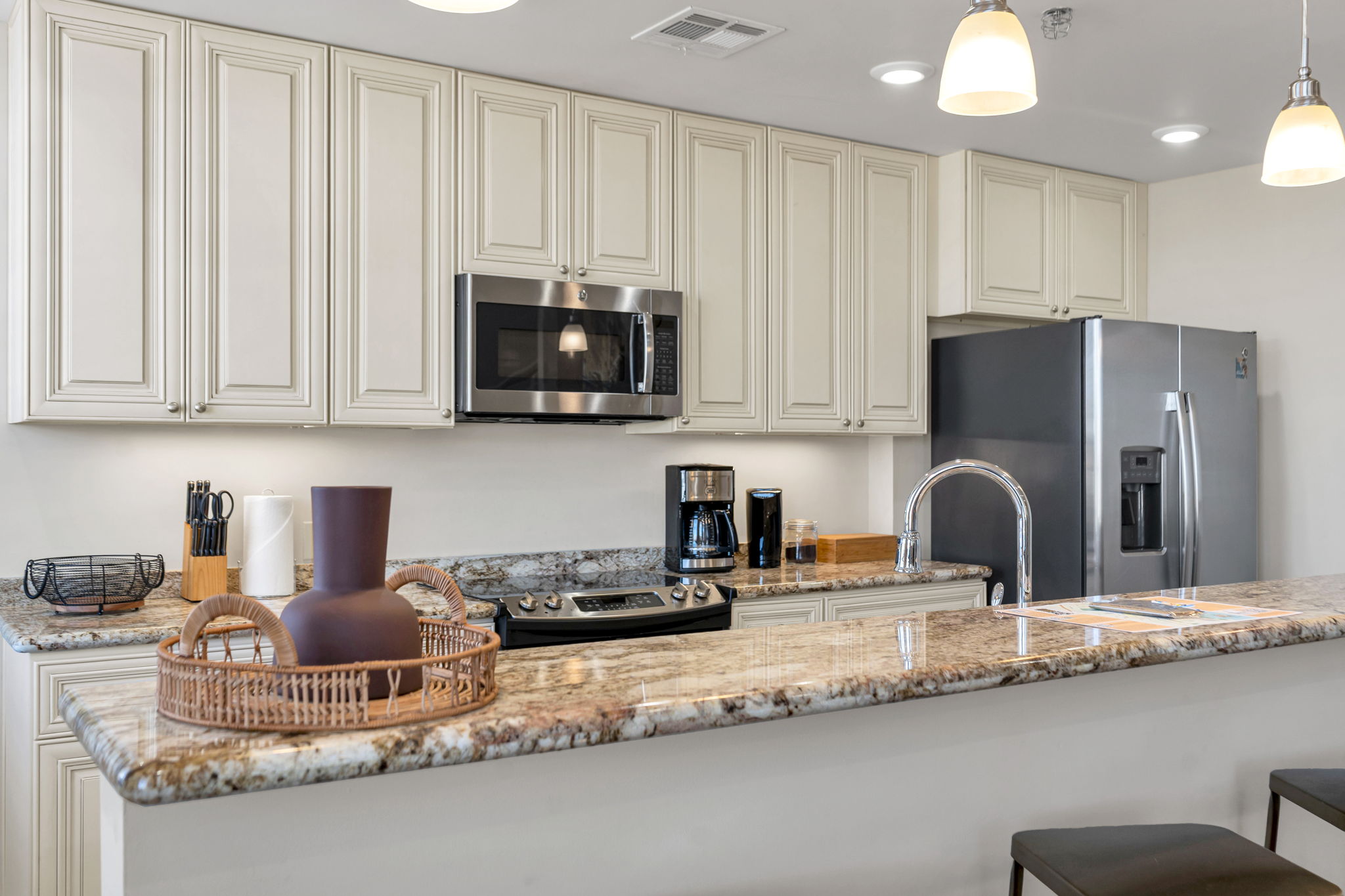 Kitchen with cream cabinets, granite counters, and stainless appliances in The Bell suite