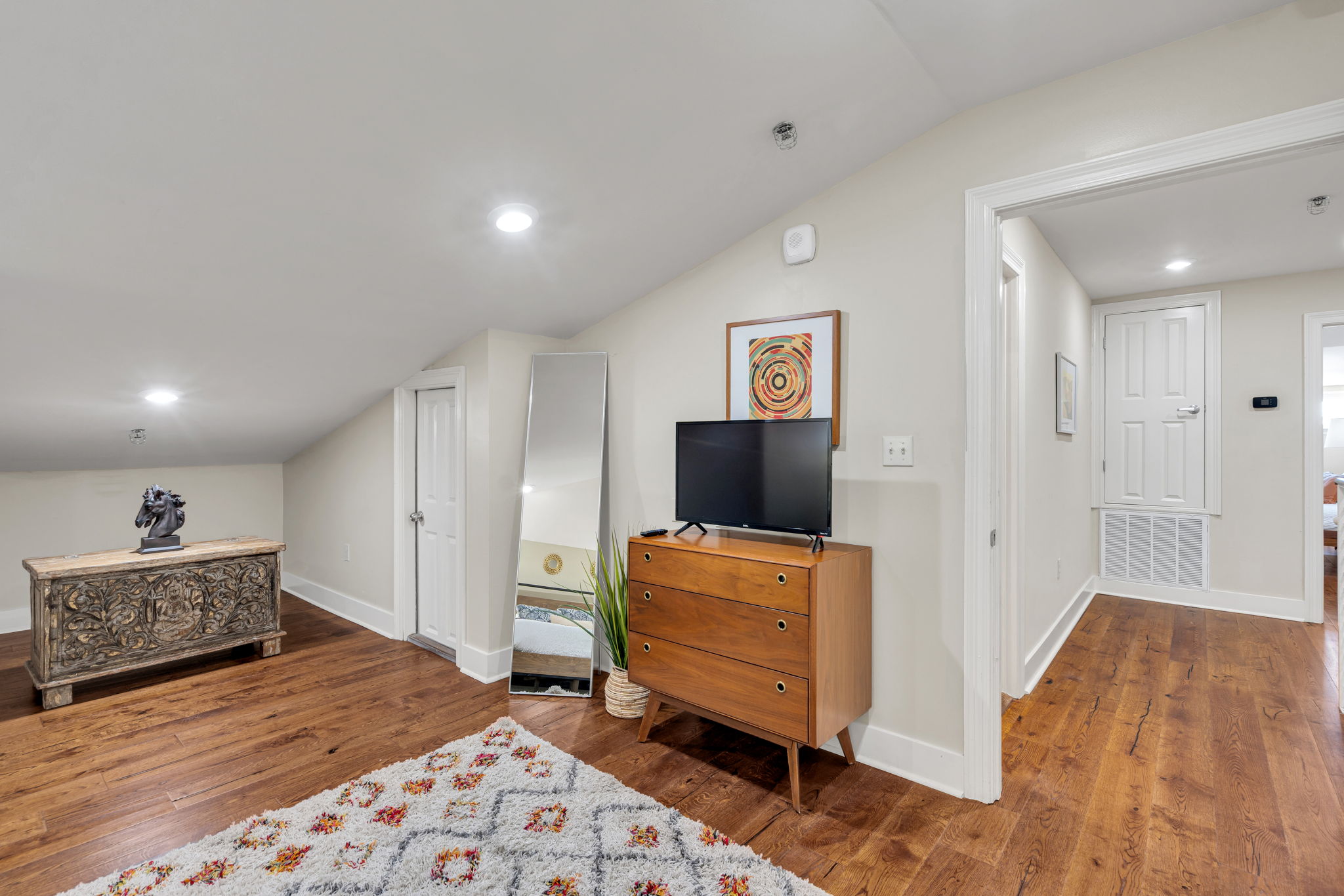 Upstairs landing with the walnut dresser, TV, and full-length mirror in The Bell suite