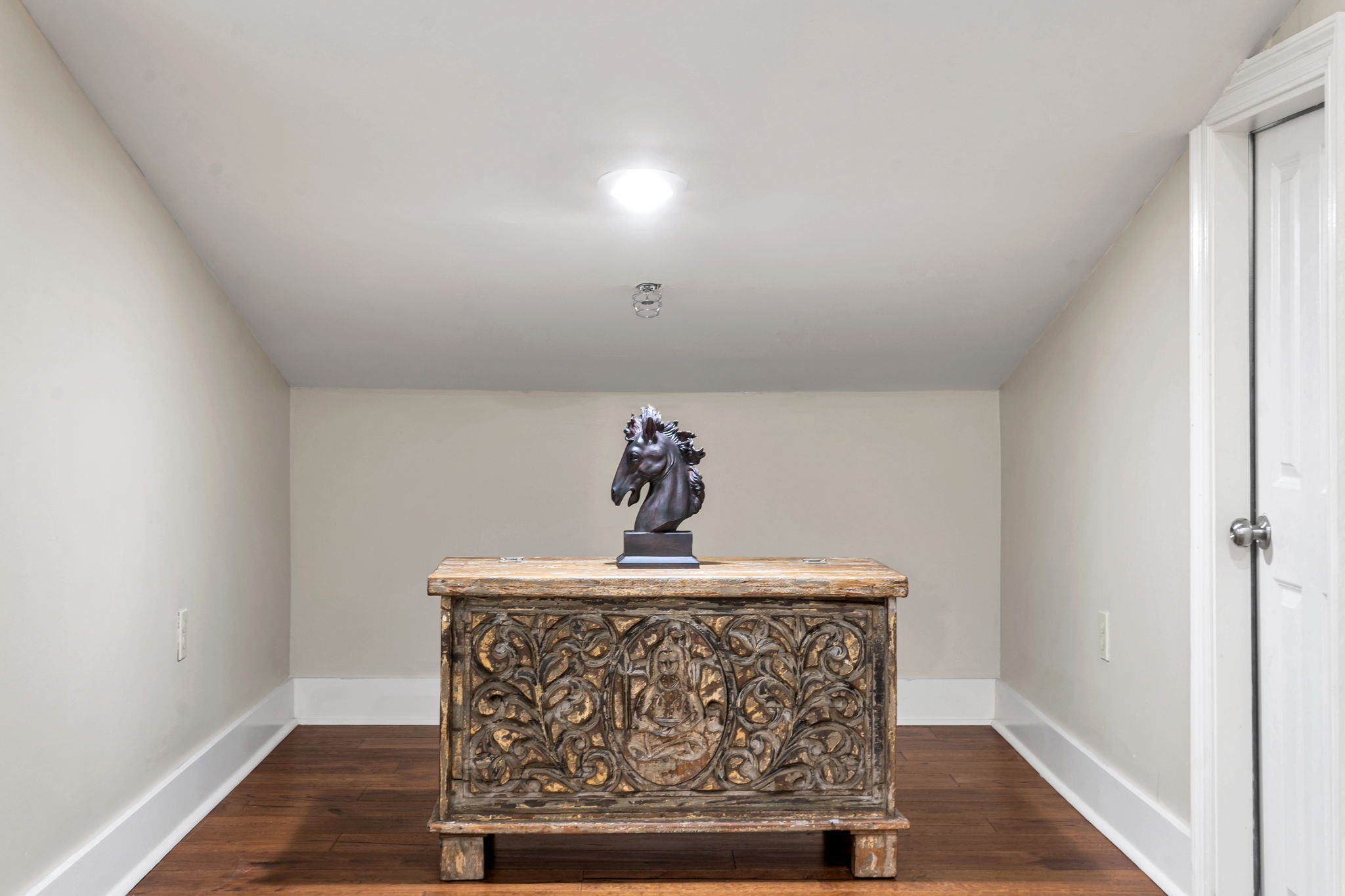 Ornately carved wooden chest topped with a horse-head sculpture in an alcove in The Bell suite