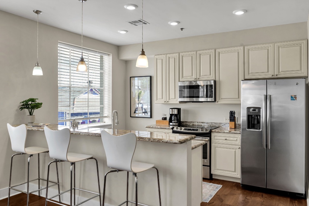 The kitchen in The Licorice suite — island with bar stools, cream cabinets, and a stainless fridge