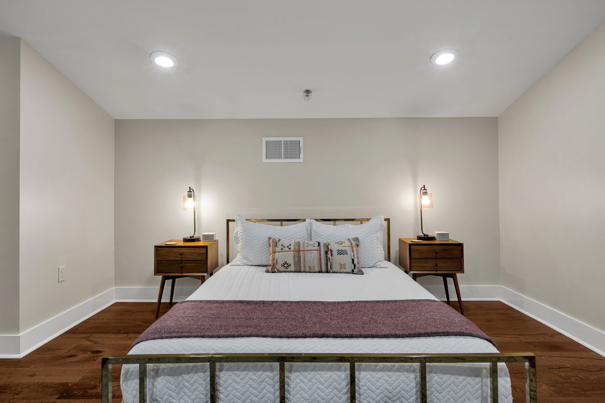 Bedroom two in The Licorice suite — brass bed frame, white bedding, and a purple throw