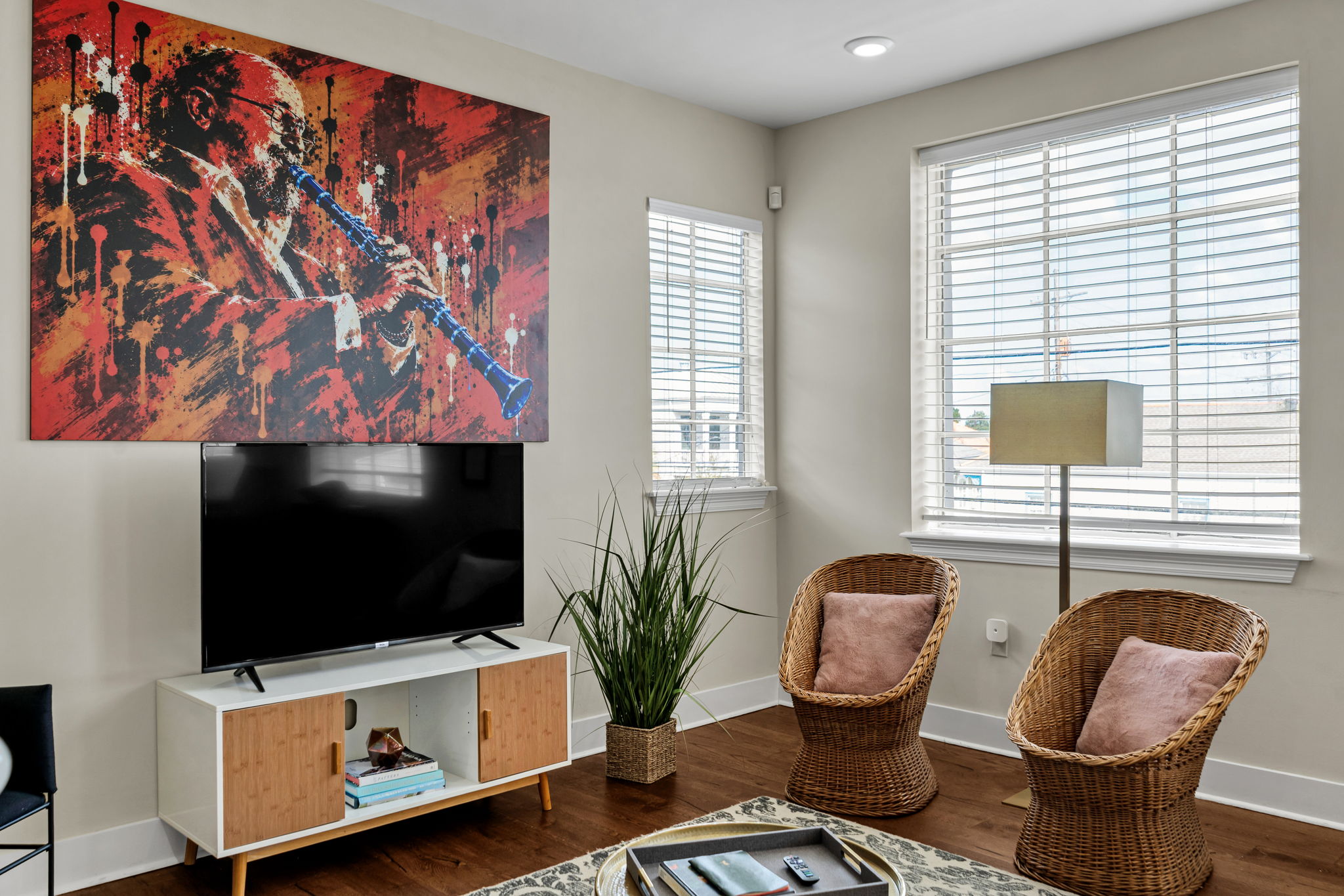 The living room in The Licorice suite — the Pete Fountain mural over the TV and wicker chairs