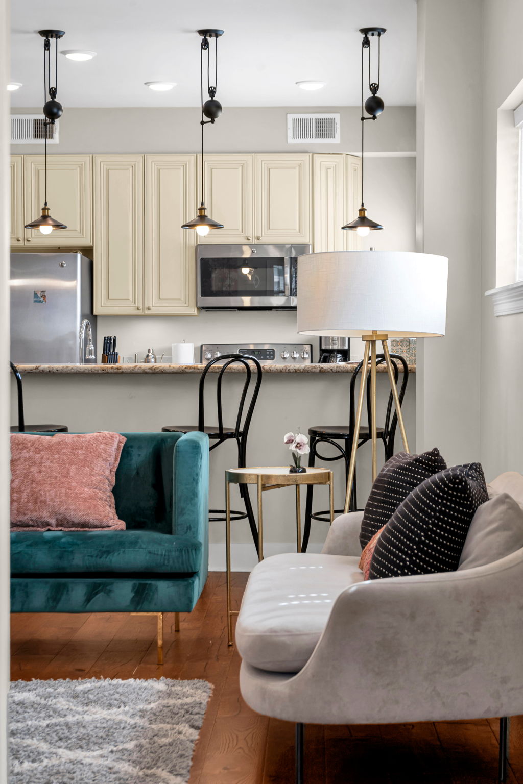 Looking from the living area toward the kitchen bar with black stools and pulley pendant lights in The Soul suite
