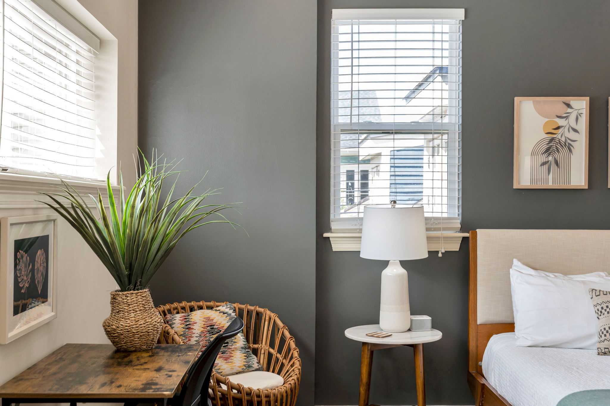 The wicker chair and wooden desk with a large potted plant beside the bedside lamp under the window in The Soul suite